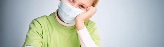 A little girl sitting in protective mask